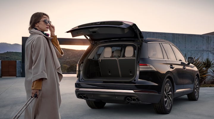 A woman approaches a 2026 Lincoln Aviator® SUV with its rear liftgate open. | Eau Claire Lincoln in Eau Claire WI
