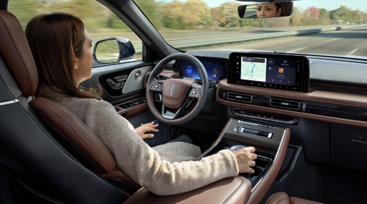 A 2026 Lincoln Aviator® SUV is being driven hands-free on a highway near a forest | Eau Claire Lincoln in Eau Claire WI