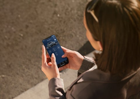 A person is shown interacting with a smartphone to connect to a Lincoln vehicle via the Lincoln Way® app. | Eau Claire Lincoln in Eau Claire WI