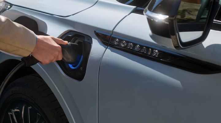 A hand is plugging in a 2026 Lincoln Corsair® Grand Touring Plug-in Hybrid SUV. | Eau Claire Lincoln in Eau Claire WI